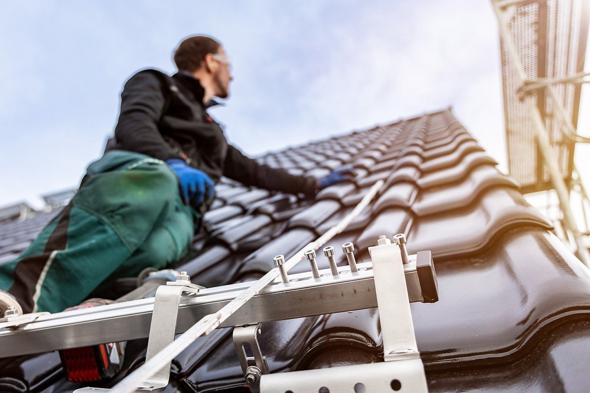 Installation von Solardachziegeln: Energieeffiziente Lösung für nachhaltige Dachmodernisierung und Photovoltaik. Montage von Solardachziegeln durch Handwerker auf modernem Hausdach – nachhaltige Photovoltaik-Integration.